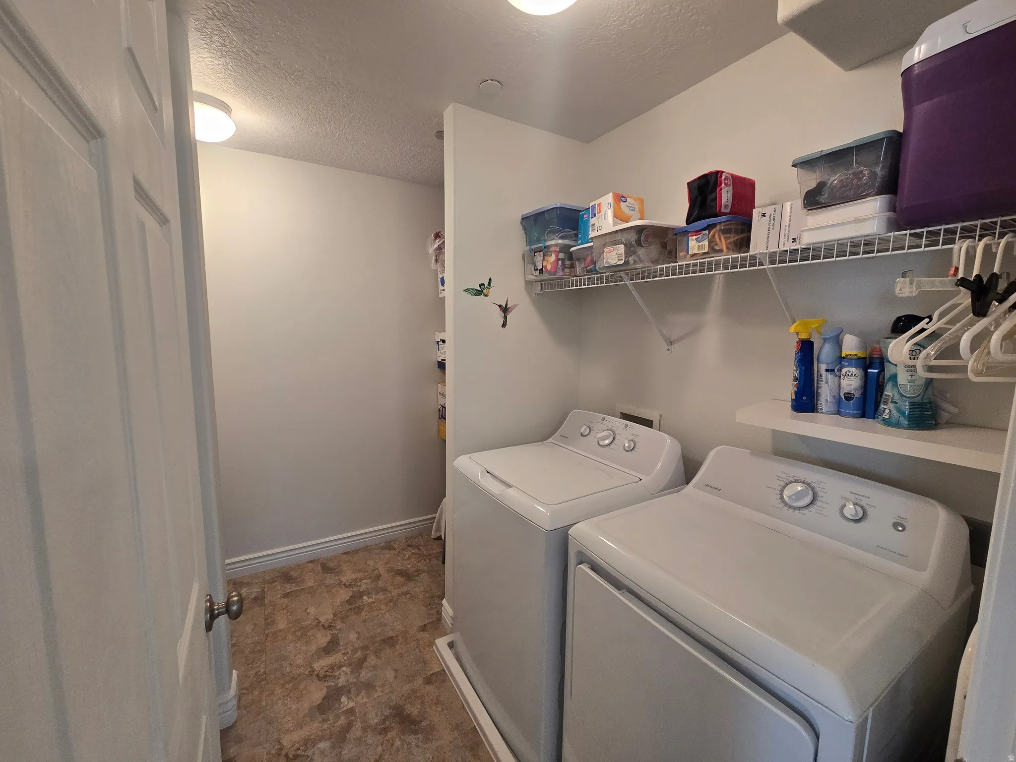 Laundry room featuring a textured ceiling, independent washer and dryer, and stone finish floors
