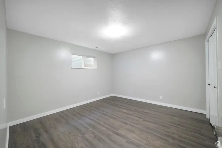 Unfurnished room with baseboards and dark wood-style floors