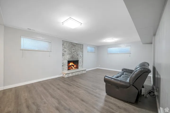 Unfurnished room with a stone fireplace and wood finished floors