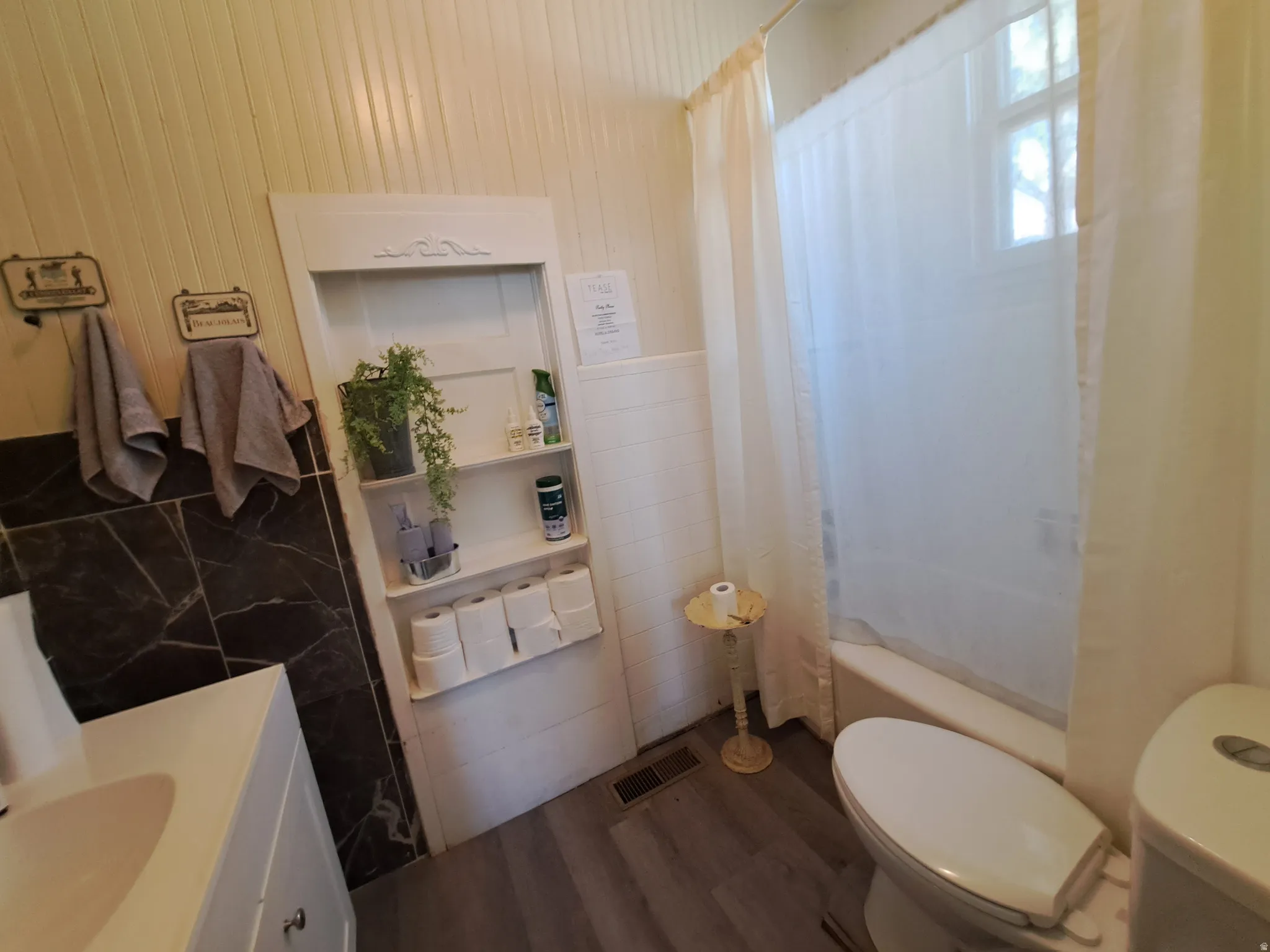Bathroom with vanity, tile walls, shower / bath combination with curtain, and dark wood-style flooring