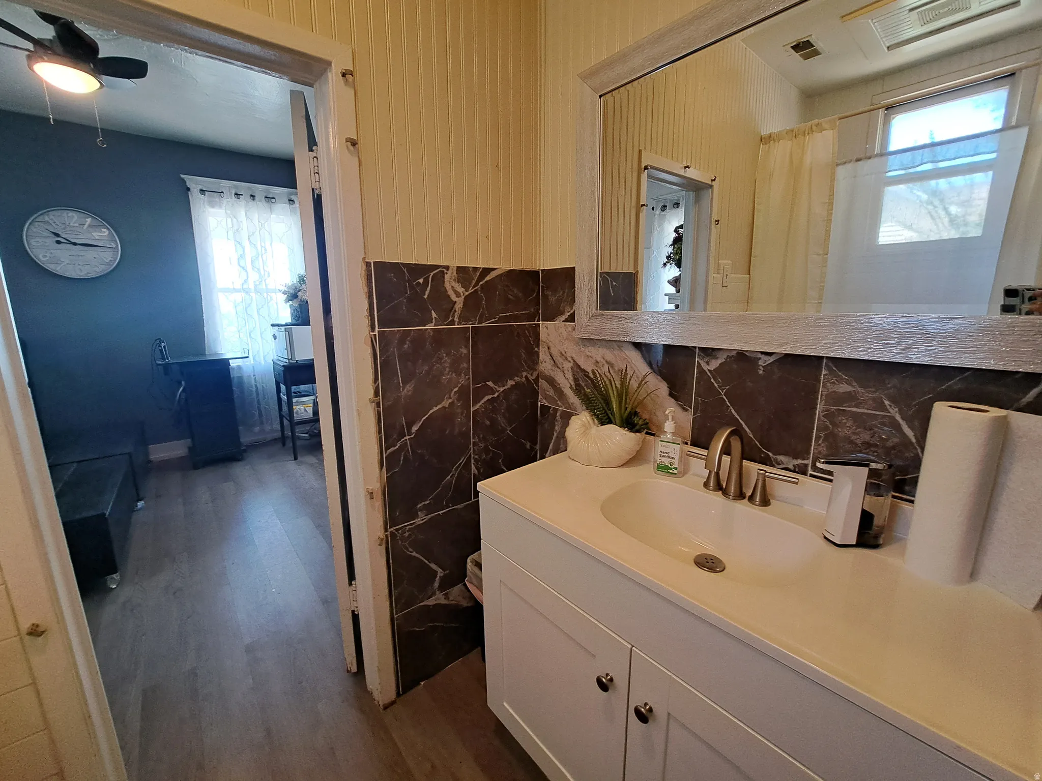 Full bathroom featuring vanity, a shower with shower curtain, dark wood-type flooring, ceiling fan, and tile walls
