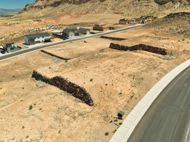 Level building lot with retaining walls, paved road access, and utility connections