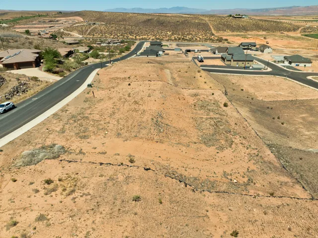 Expansive undeveloped land with a paved road and sidewalk