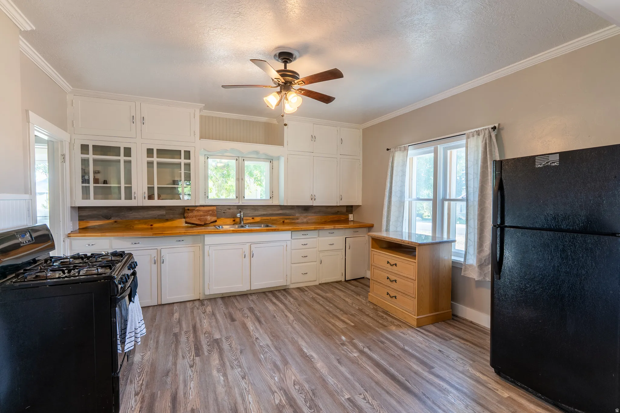 Kitchen featuring black appliances, wood counters, ornamental molding, ceiling fan, and light wood-style floors
