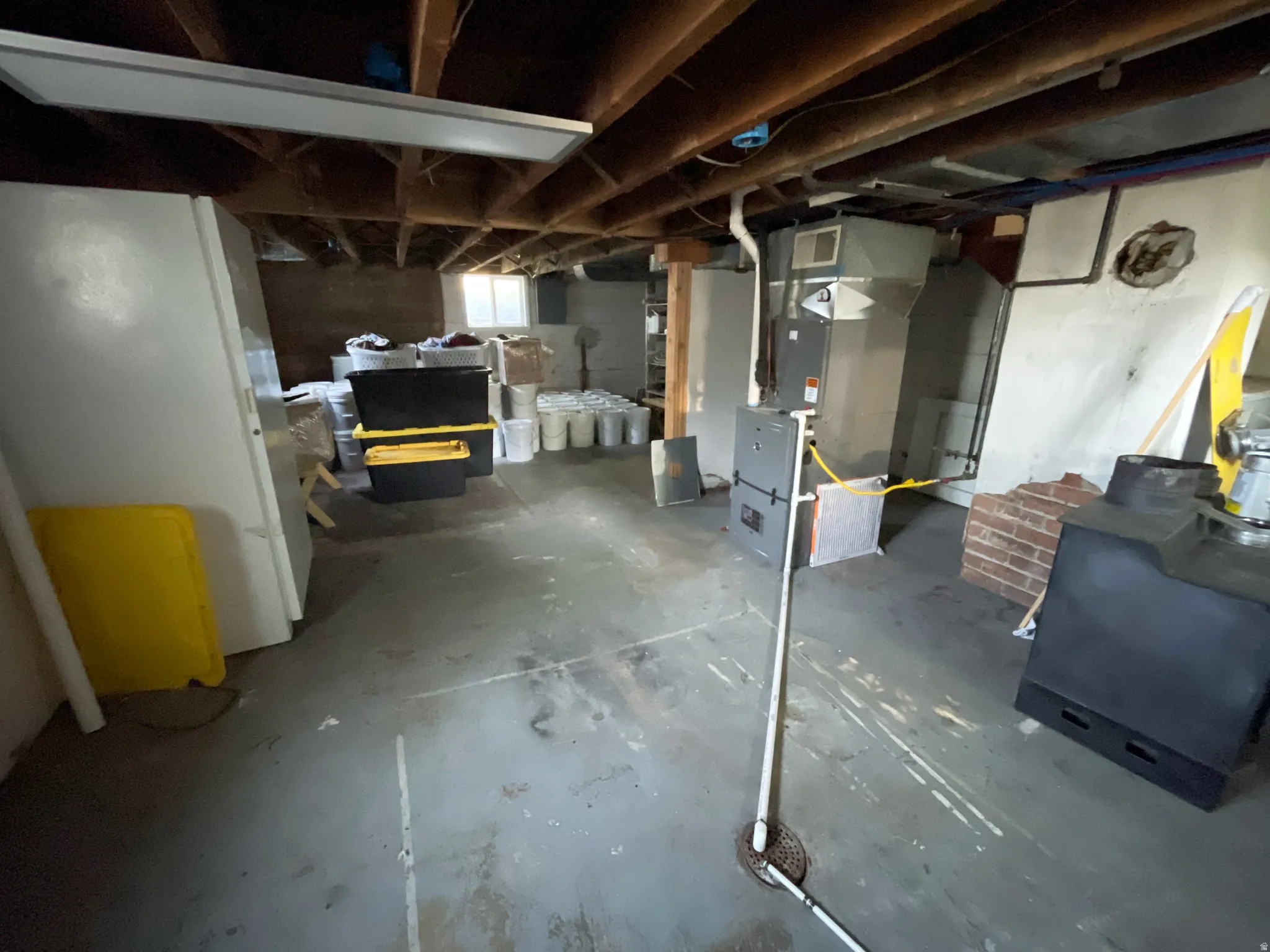 Basement with freestanding refrigerator and heating unit