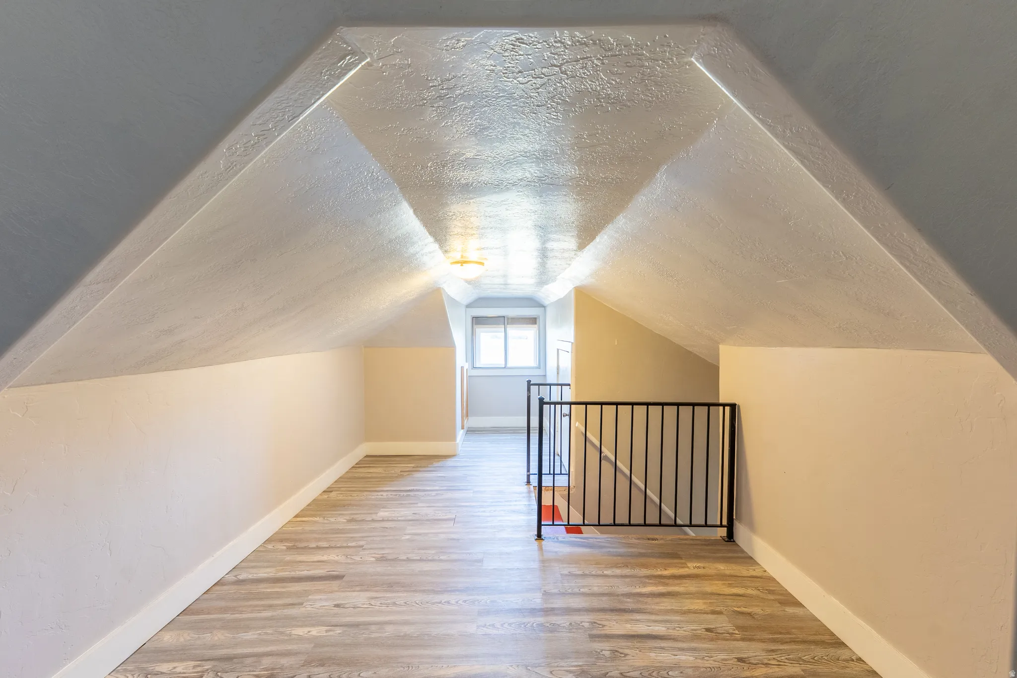 Bonus room with light wood-style floors and a textured ceiling