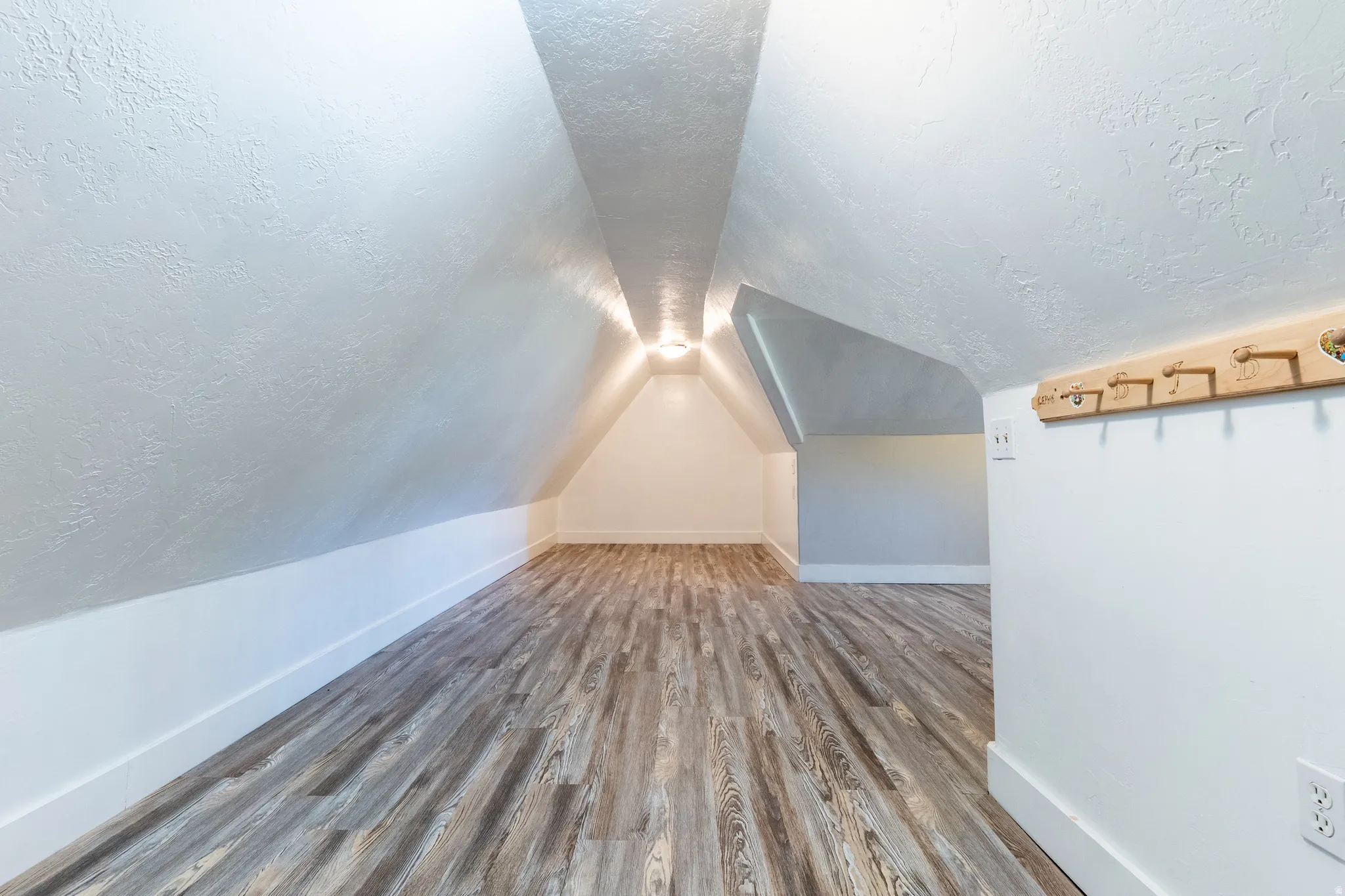 Additional living space with a textured ceiling and dark wood-type flooring