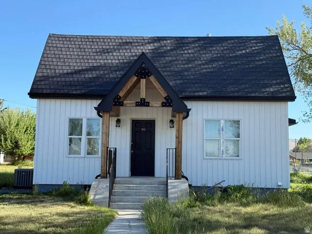 View of front facade with a shingled roof and a front lawn