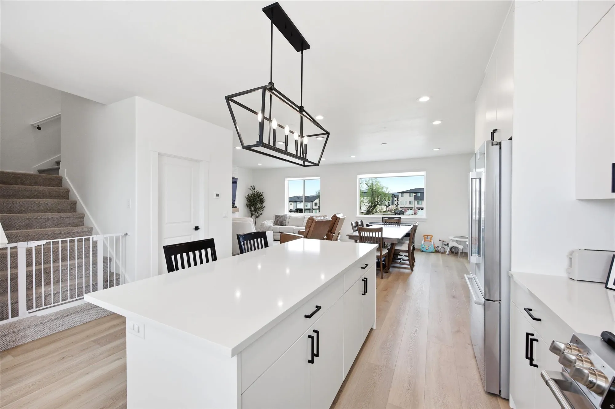 Kitchen featuring white cabinetry, light wood-style flooring, a kitchen island, stainless steel appliances, and a chandelier