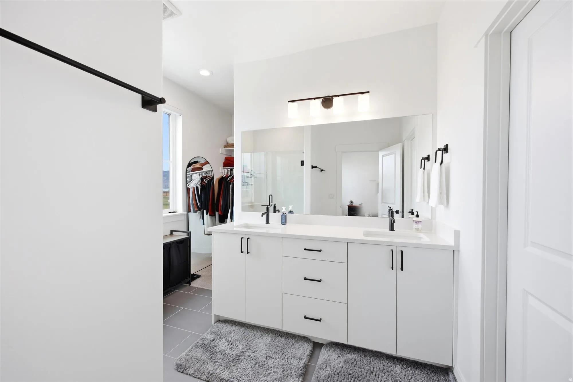 Full bathroom with double vanity, a spacious closet, light tile patterned floors, and recessed lighting