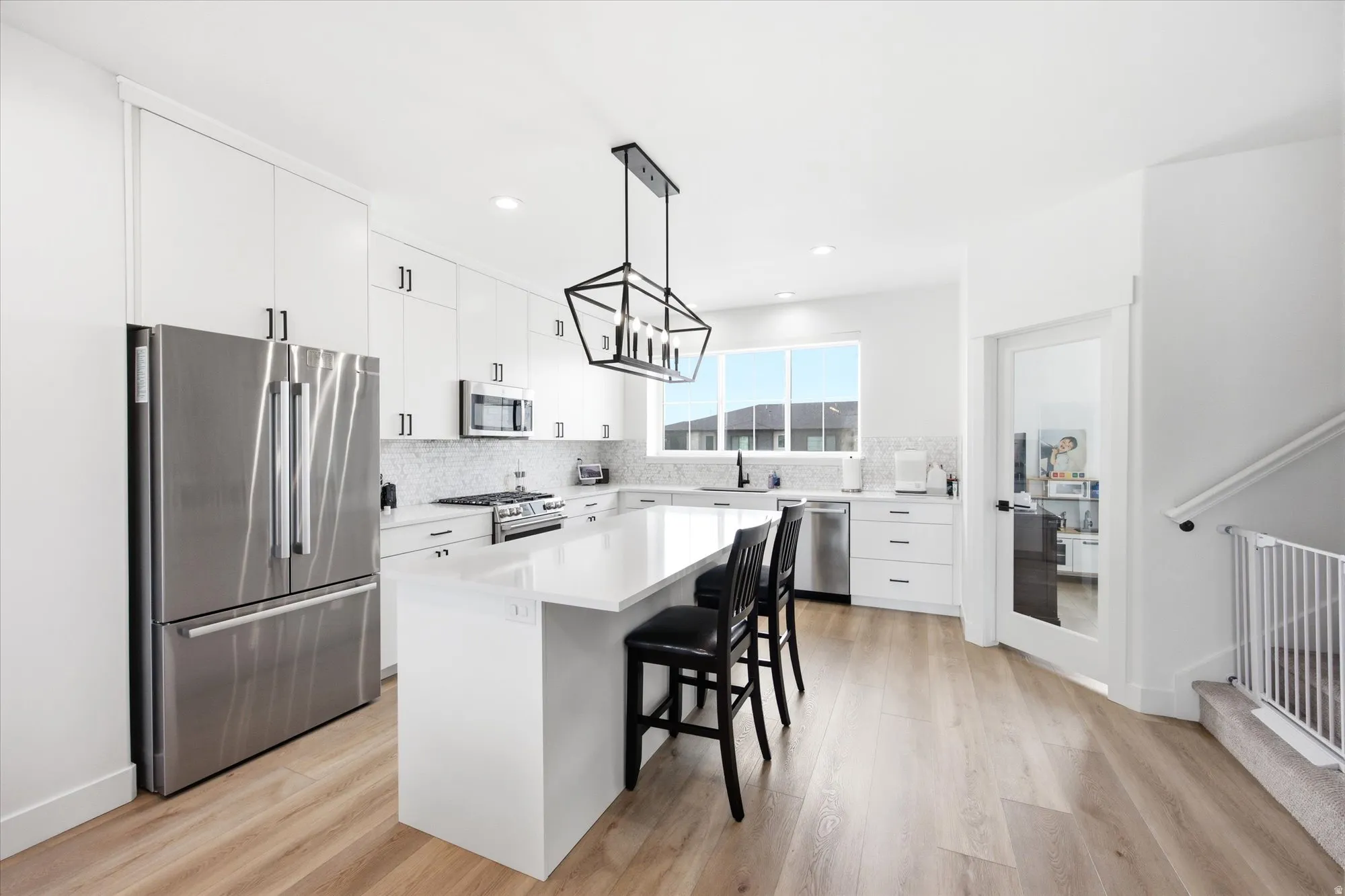 Kitchen featuring stainless steel appliances, white cabinets, a kitchen breakfast bar, a kitchen island, and light wood-style floors