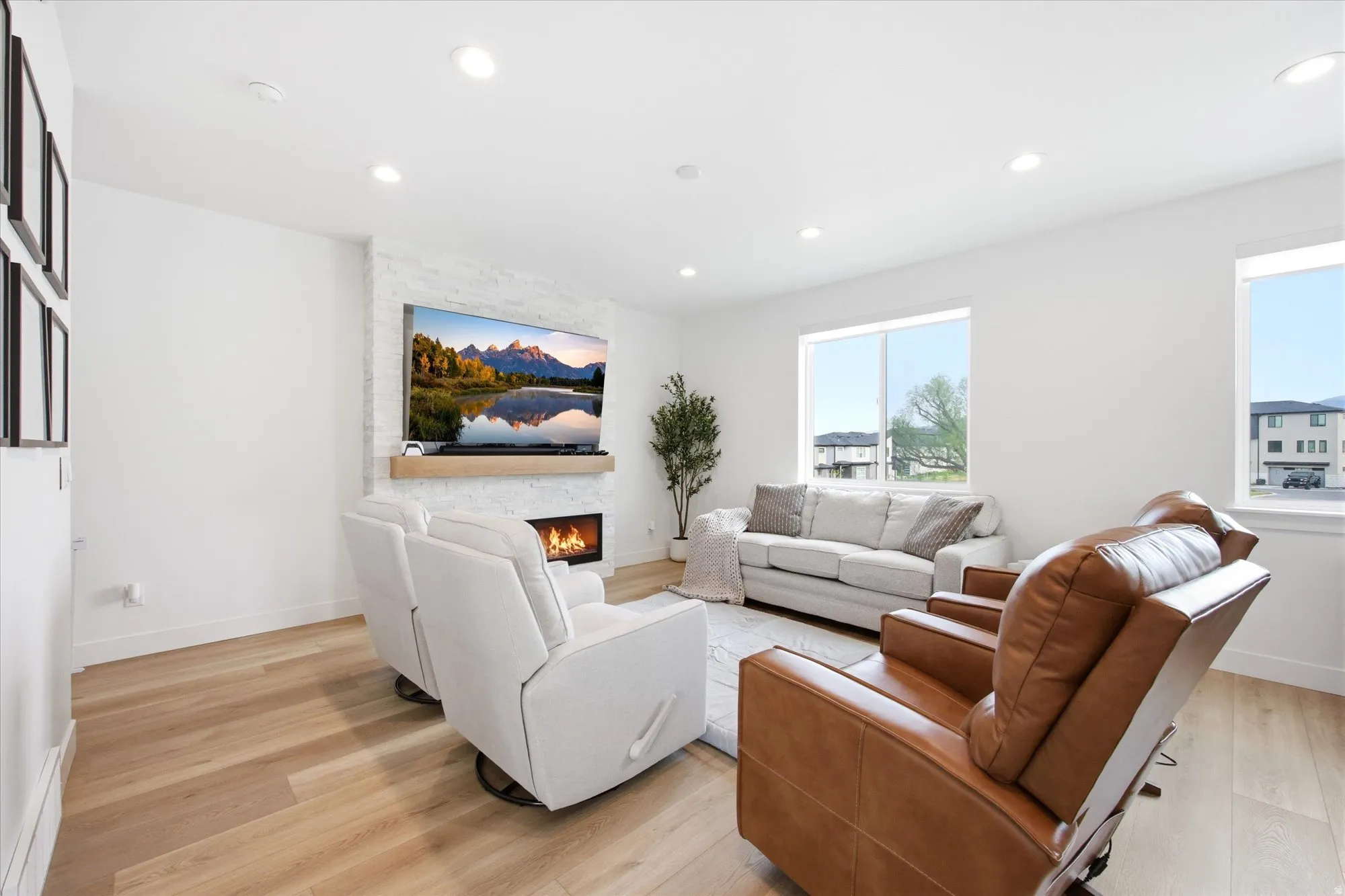 Living room featuring light wood finished floors, a stone fireplace, and recessed lighting