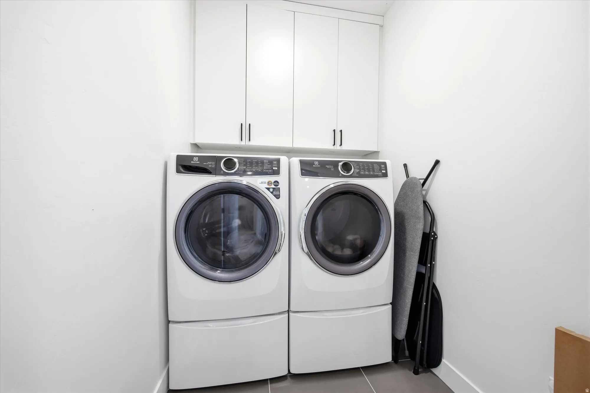 Laundry area featuring cabinet space, washer and dryer, and light tile patterned floors