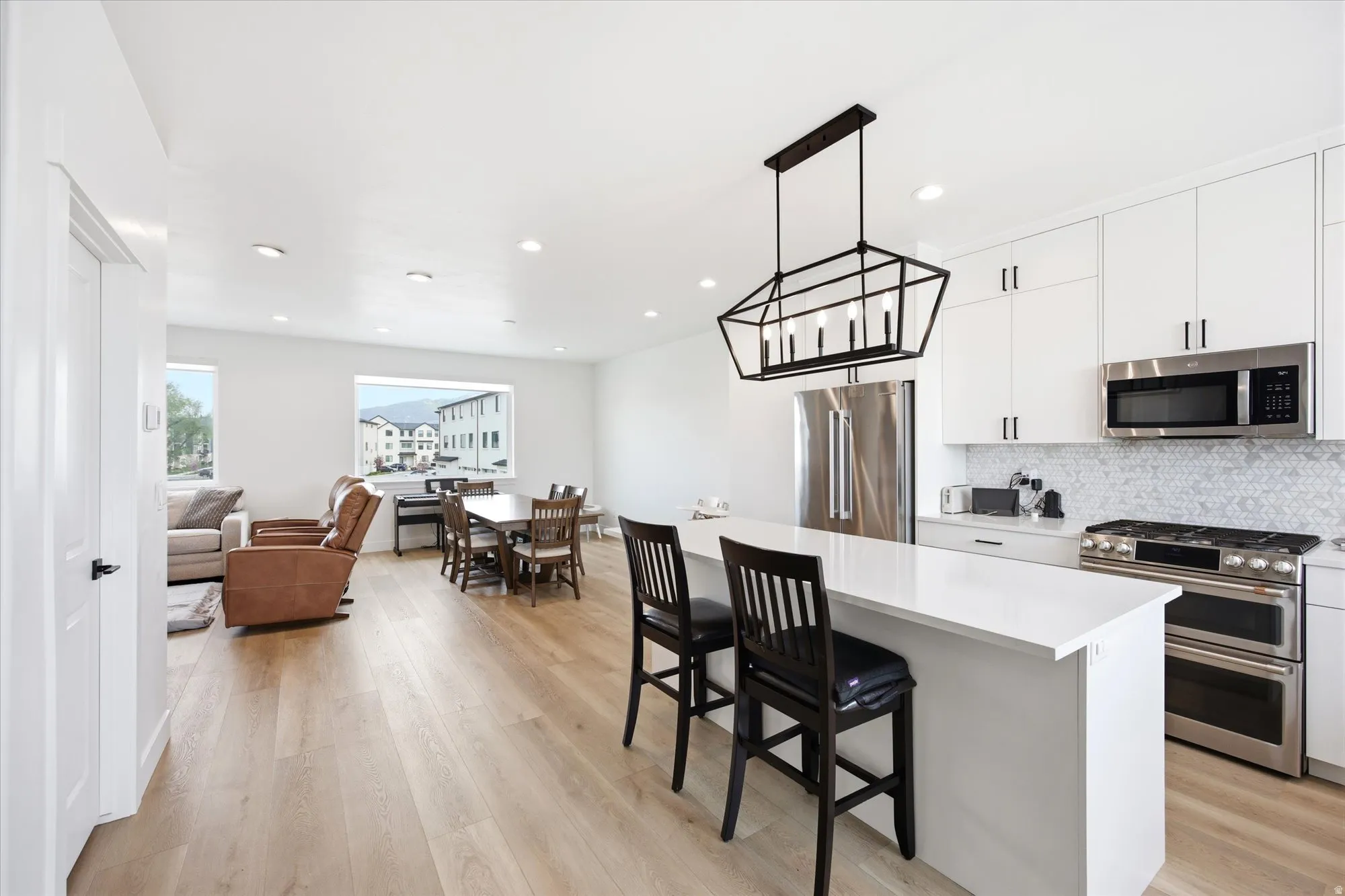 Kitchen with stainless steel appliances, white cabinets, a kitchen bar, a center island, and tasteful backsplash