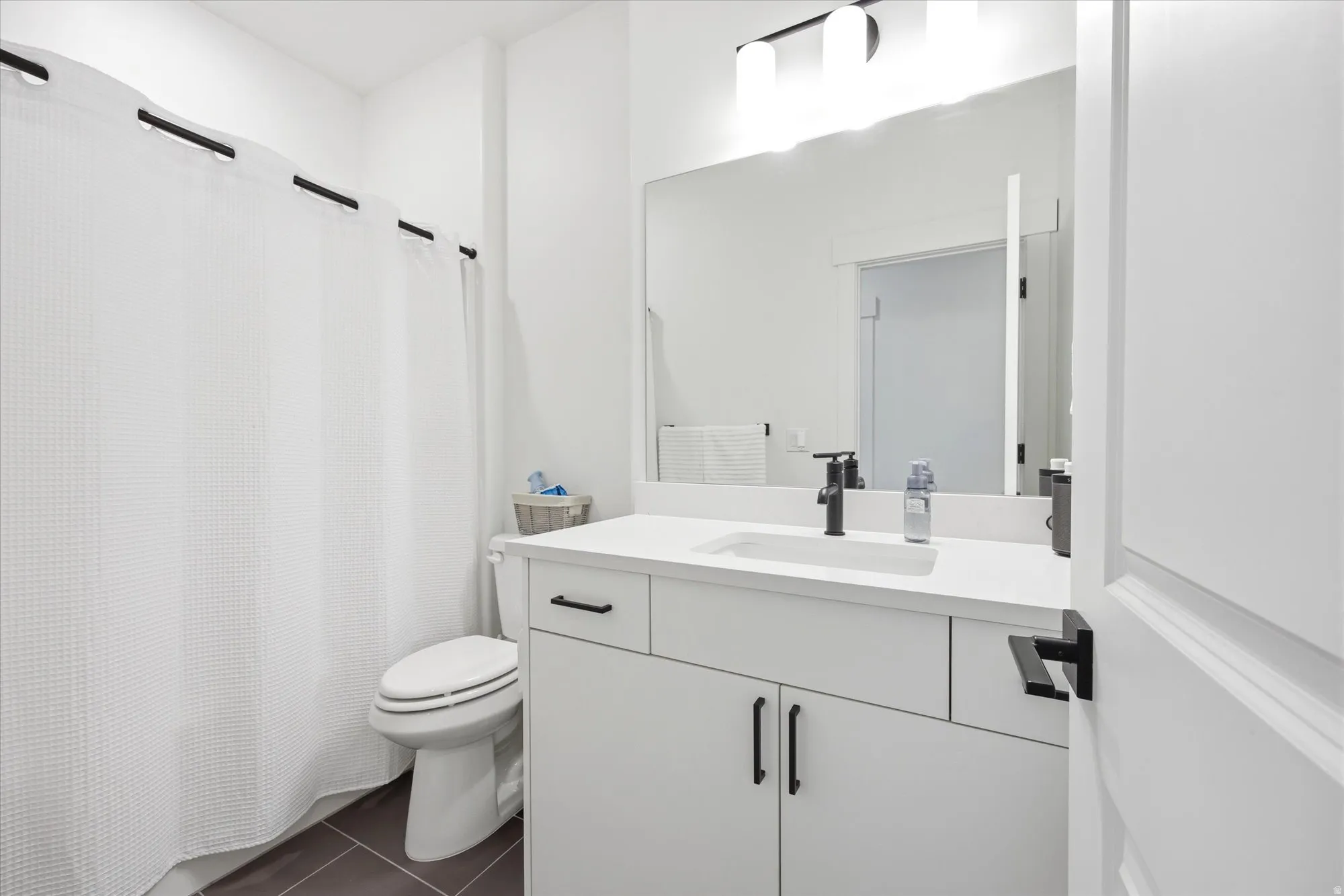 Bathroom featuring vanity, a shower with curtain, and dark tile patterned floors