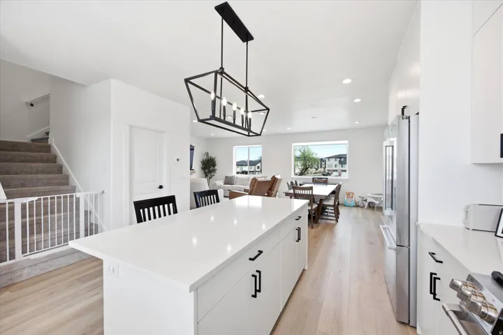 Kitchen featuring white cabinetry, light wood-style flooring, a kitchen island, stainless steel appliances, and a chandelier