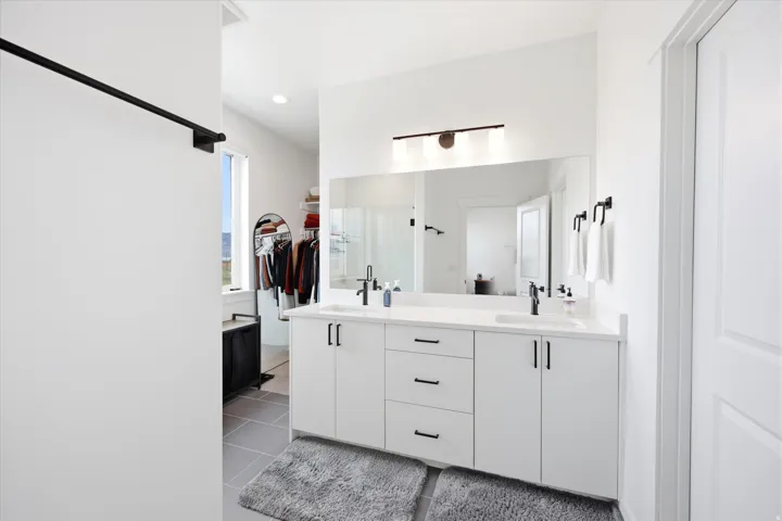 Full bathroom with double vanity, a spacious closet, light tile patterned floors, and recessed lighting