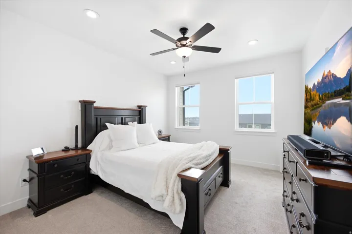 Bedroom featuring light colored carpet, a ceiling fan, and recessed lighting