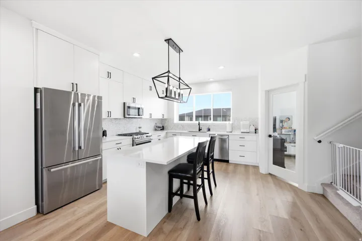 Kitchen featuring stainless steel appliances, white cabinets, a kitchen breakfast bar, a kitchen island, and light wood-style floors