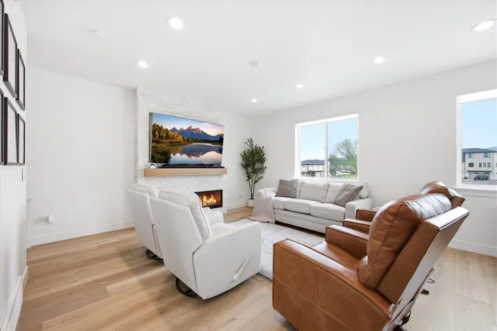 Living room featuring light wood finished floors, a stone fireplace, and recessed lighting