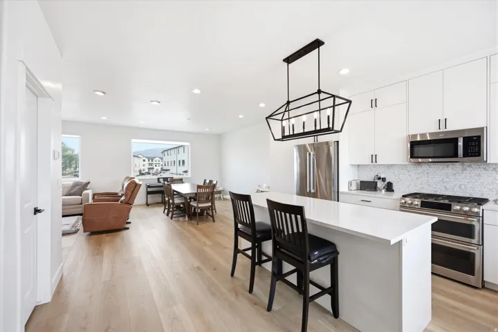 Kitchen with stainless steel appliances, white cabinets, a kitchen bar, a center island, and tasteful backsplash