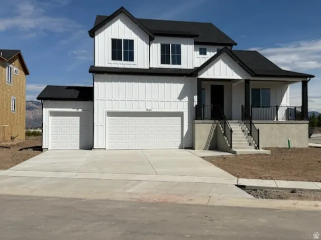 Modern farmhouse with covered porch, driveway, board and batten siding, and a garage