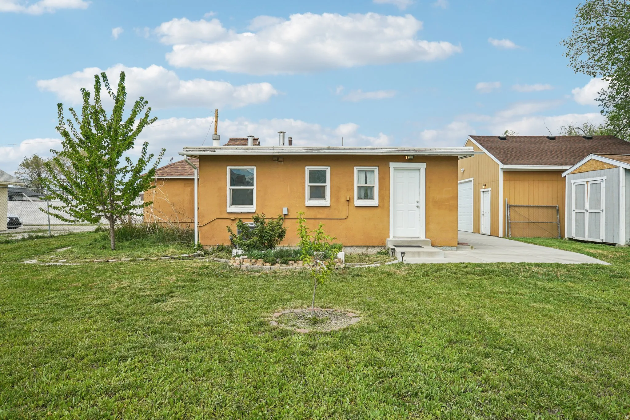 Back of property with stucco siding, a storage unit, and a patio area