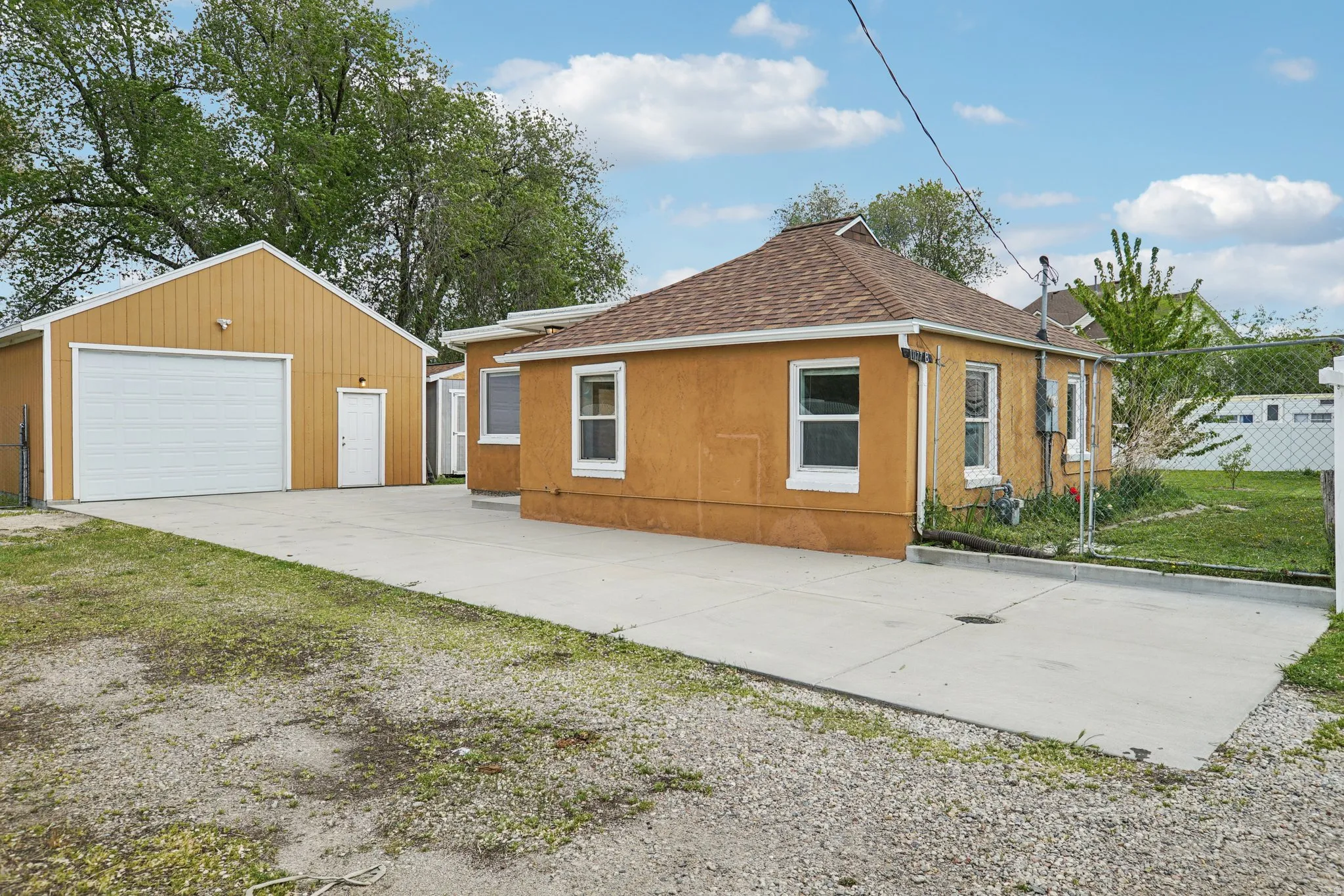 View of side of property with a shingled roof, a garage, an outdoor structure, driveway, and a yard
