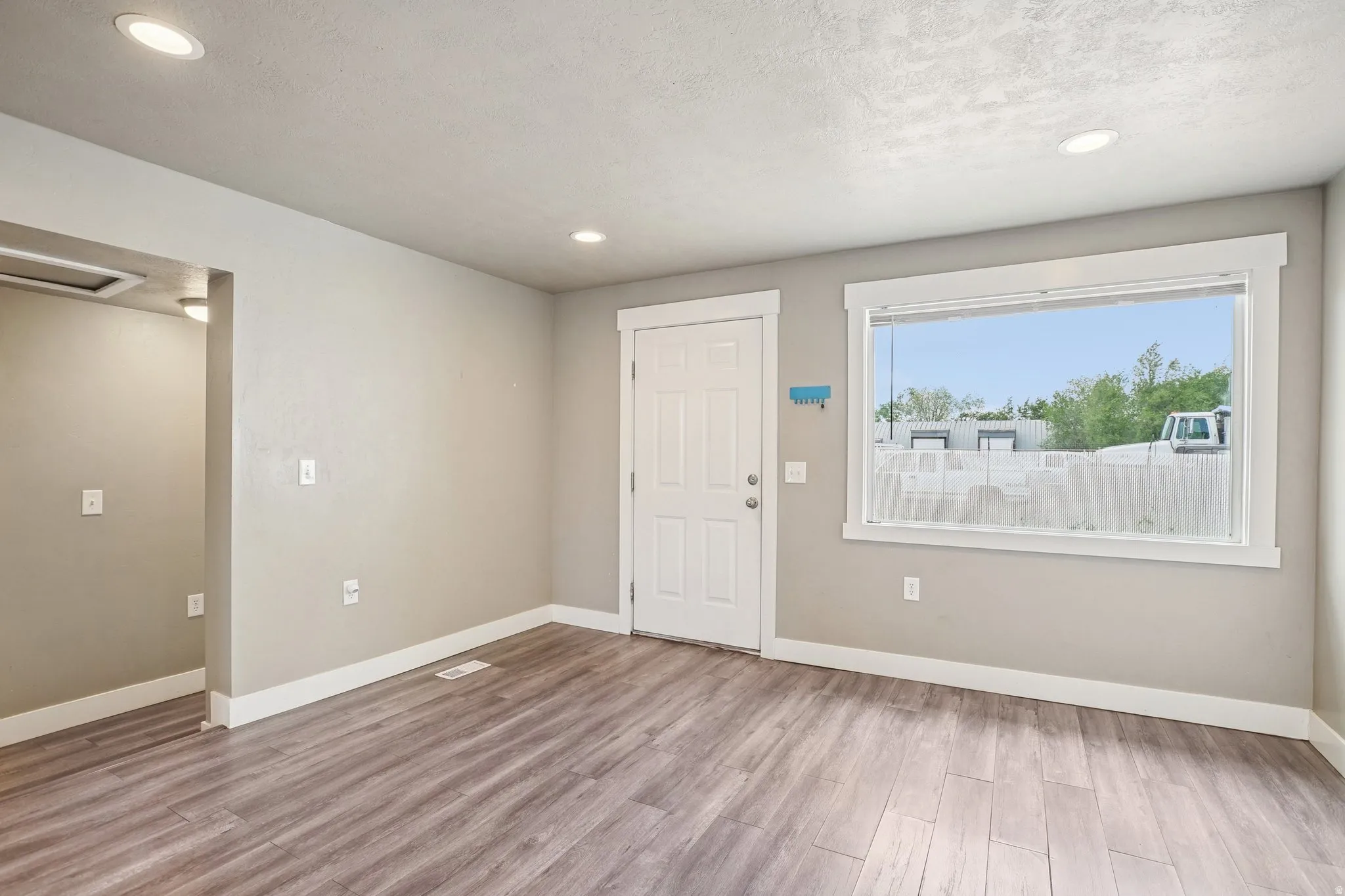 Foyer entrance with light wood-type flooring, recessed lighting, and a textured ceiling