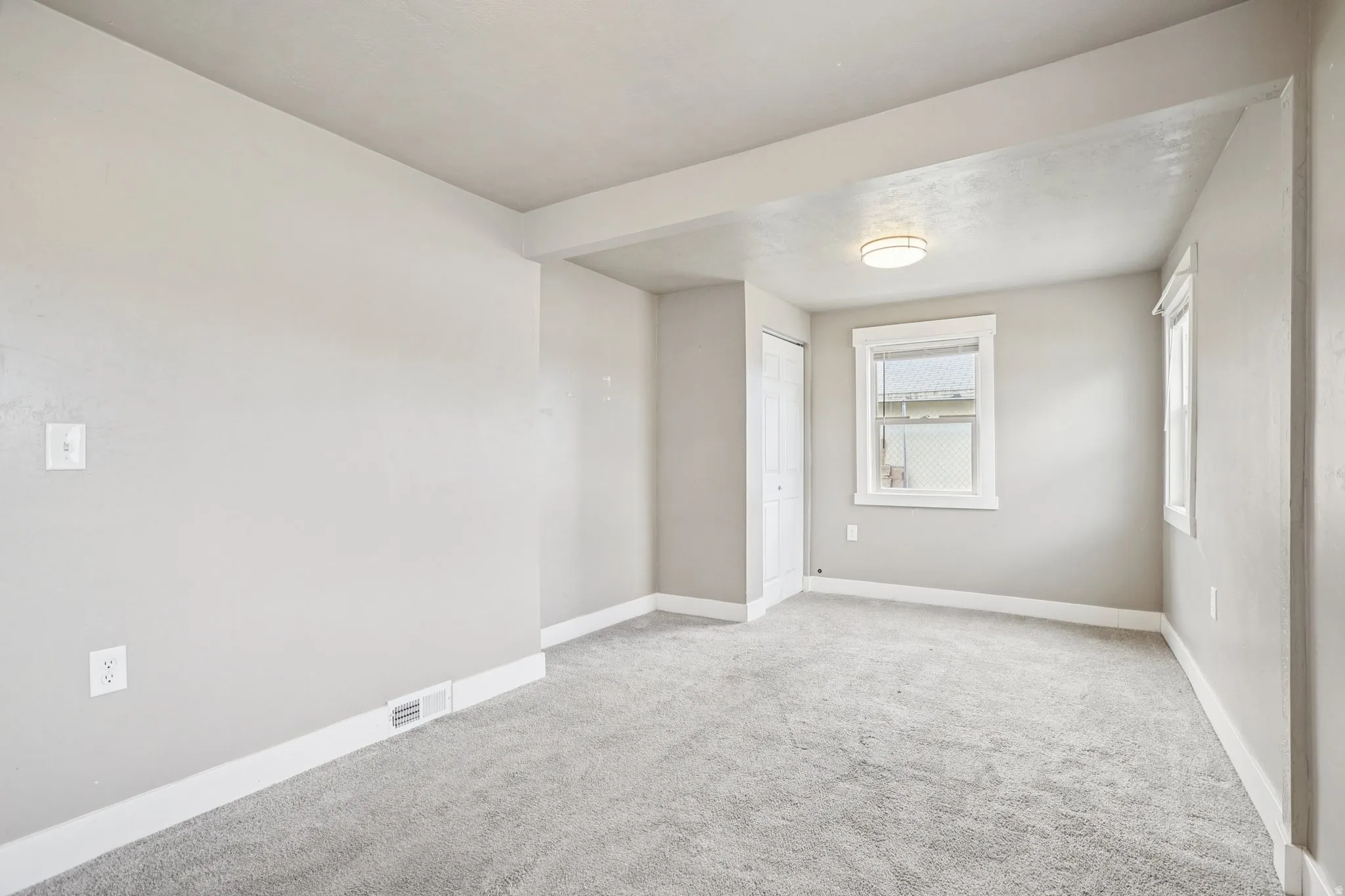 Spare room with light carpet and baseboards