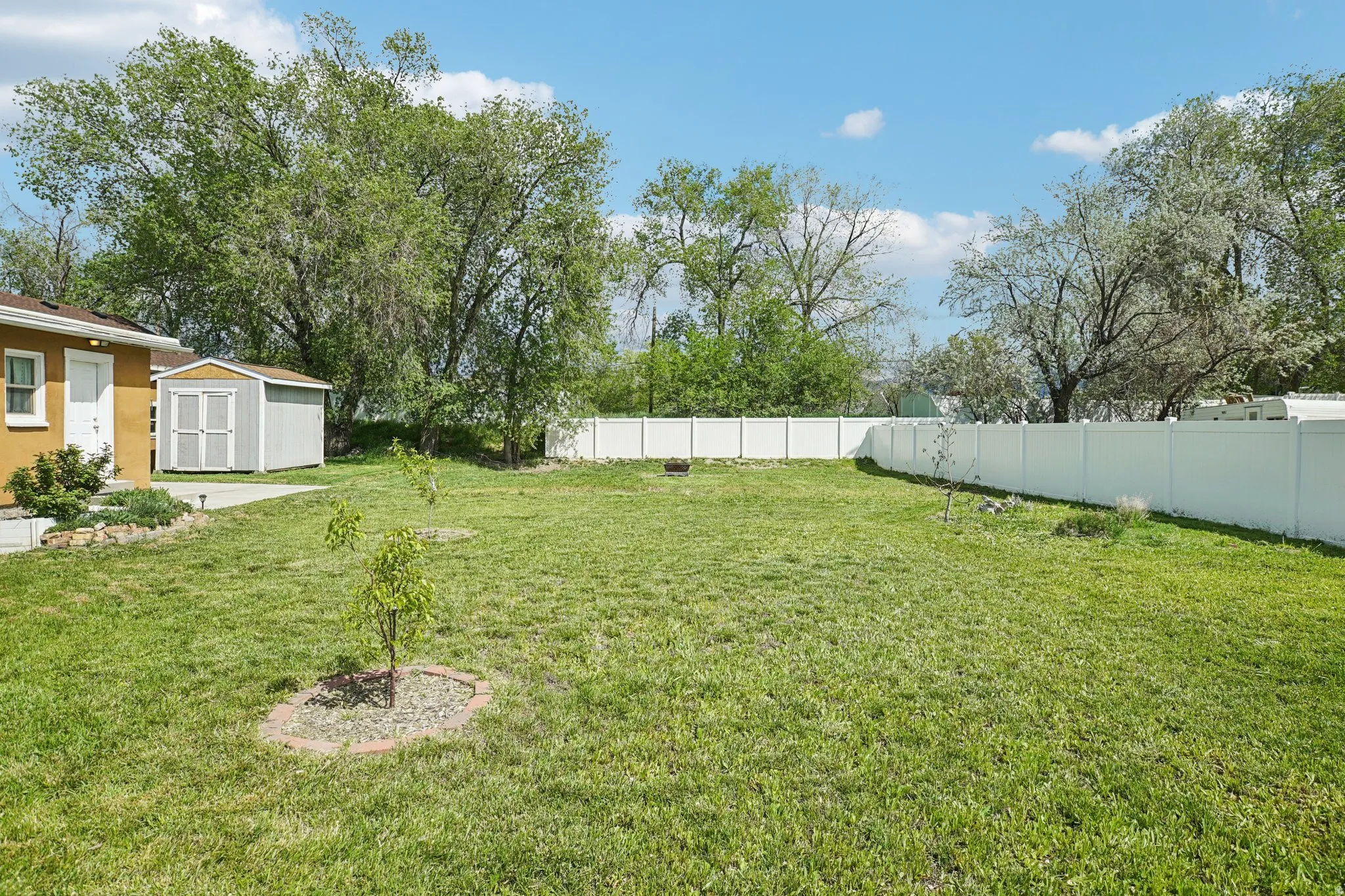 Fenced backyard featuring a storage unit