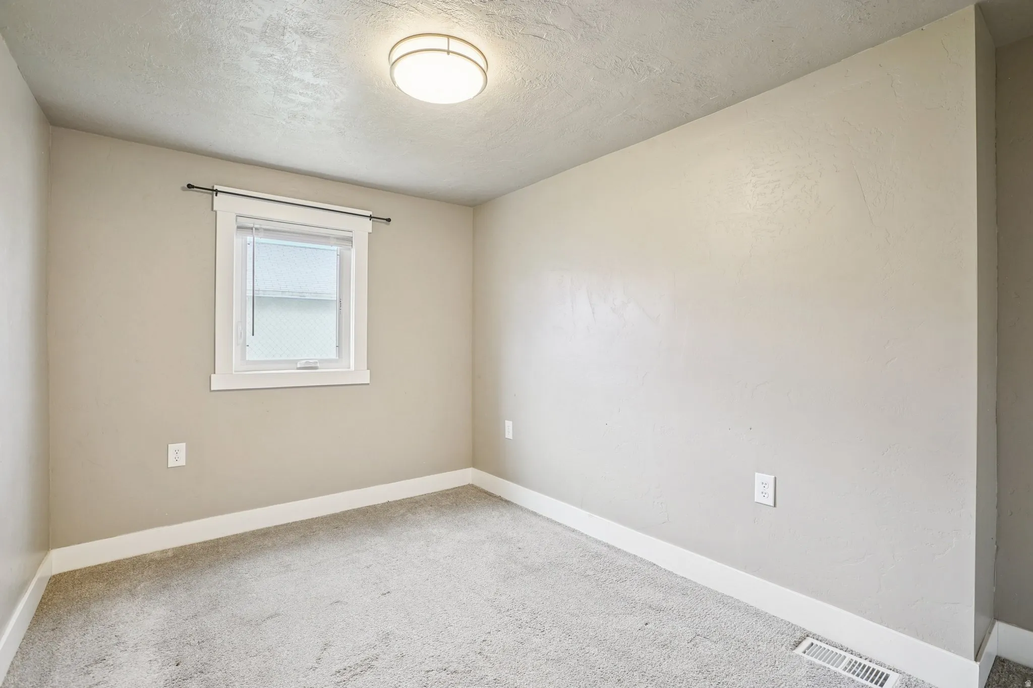 Spare room with light carpet and a textured ceiling