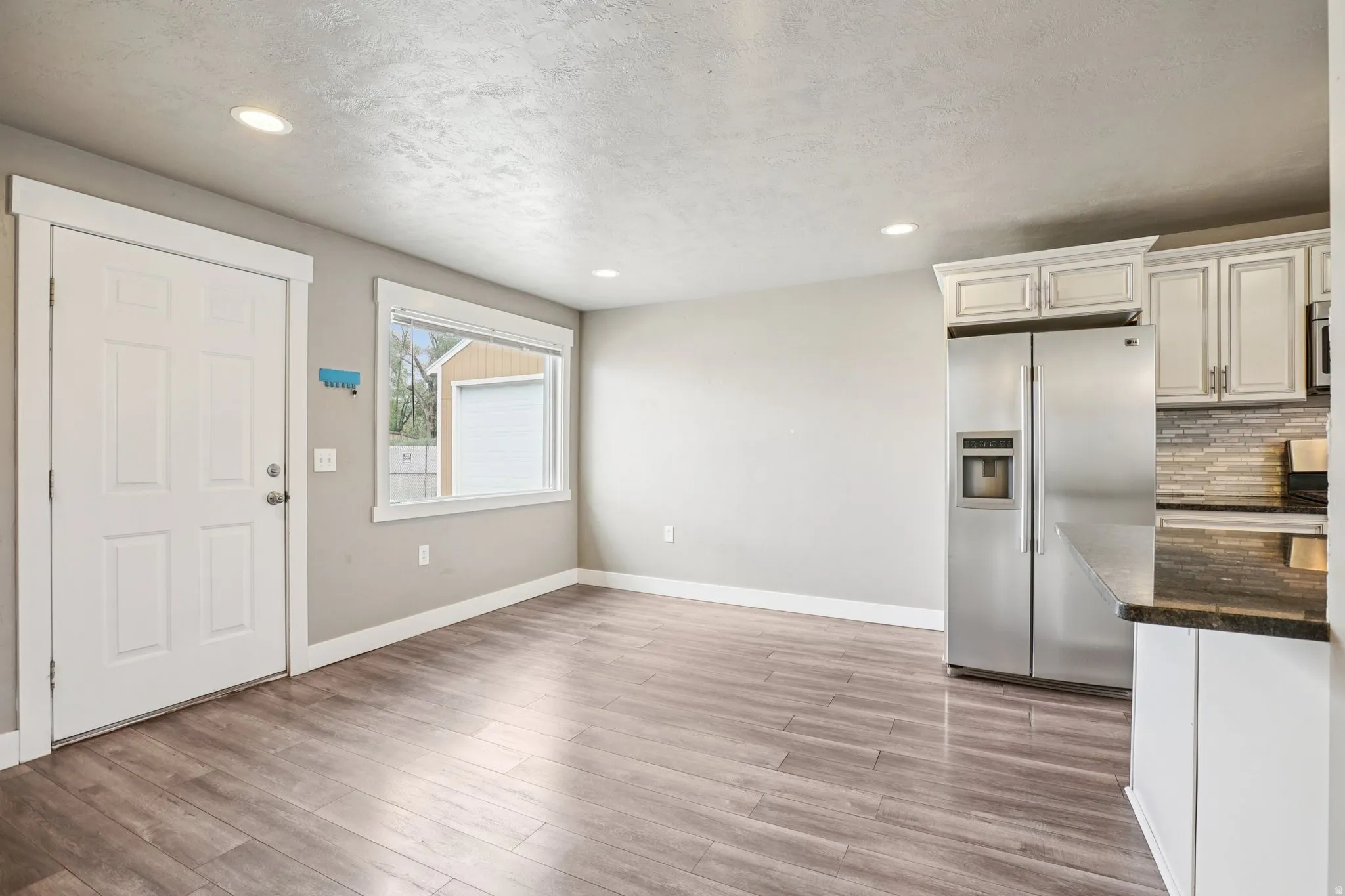 Foyer entrance with light wood-style floors, recessed lighting, and a textured ceiling