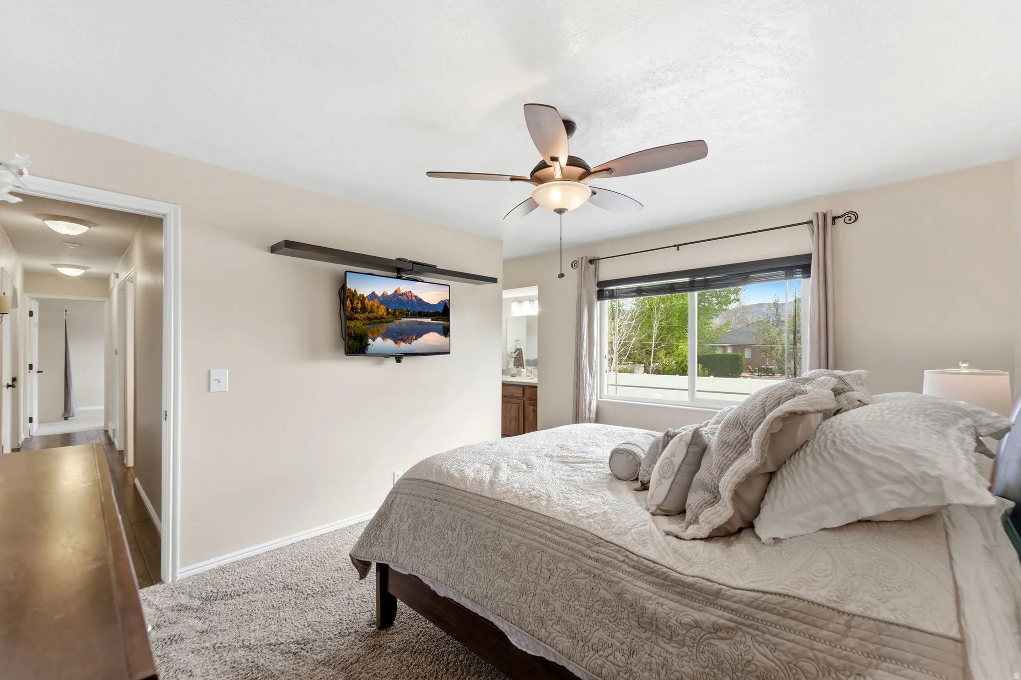 Bedroom with carpet floors, connected bathroom, and a ceiling fan