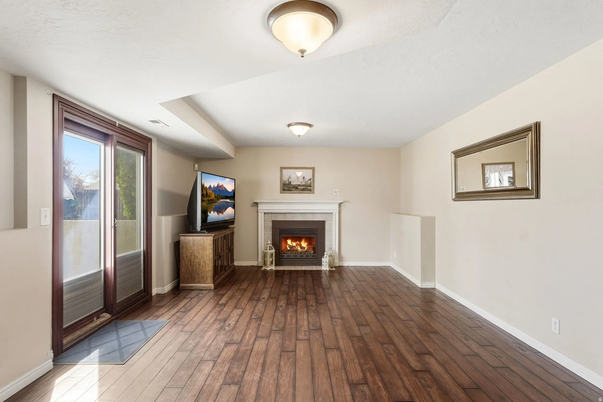 Unfurnished living room featuring dark wood-type flooring and a tiled fireplace