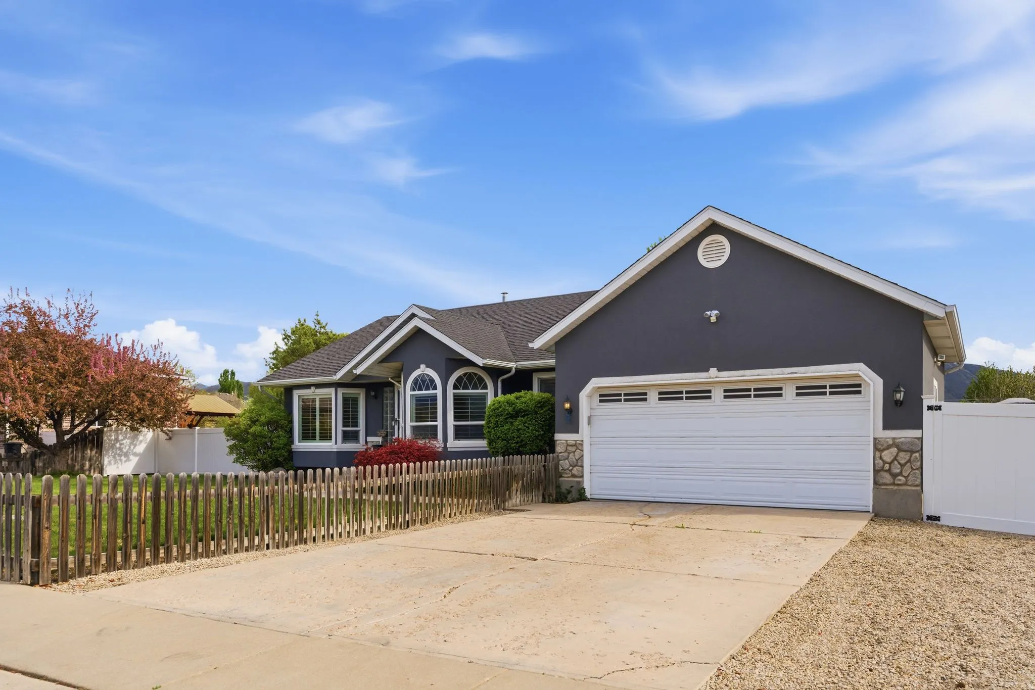 Single story home with a fenced front yard, stone siding, concrete driveway, and an attached garage