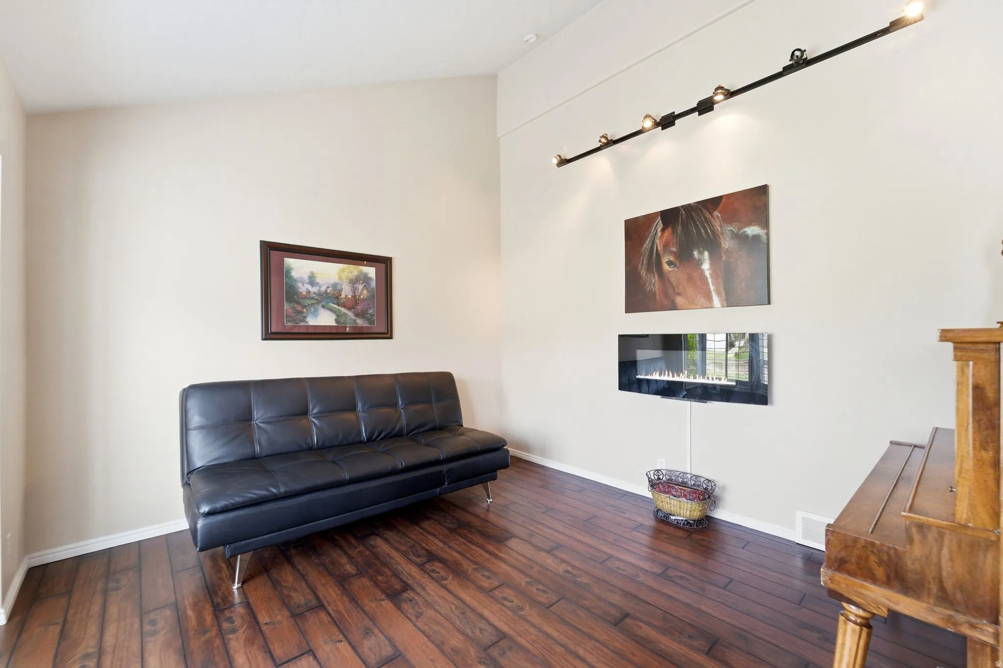 Sitting room featuring dark wood finished floors, a glass covered fireplace, and lofted ceiling