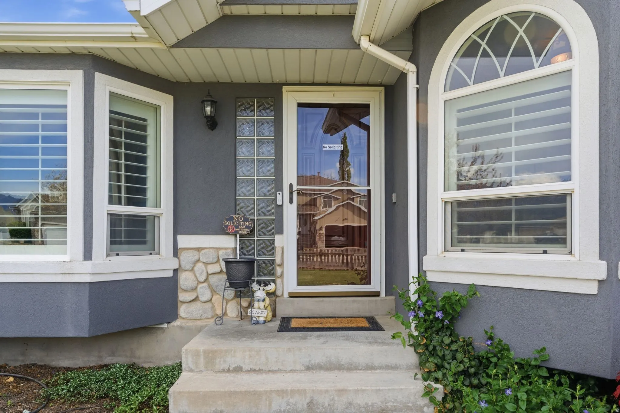 Property entrance featuring covered porch, stucco siding, and stone siding