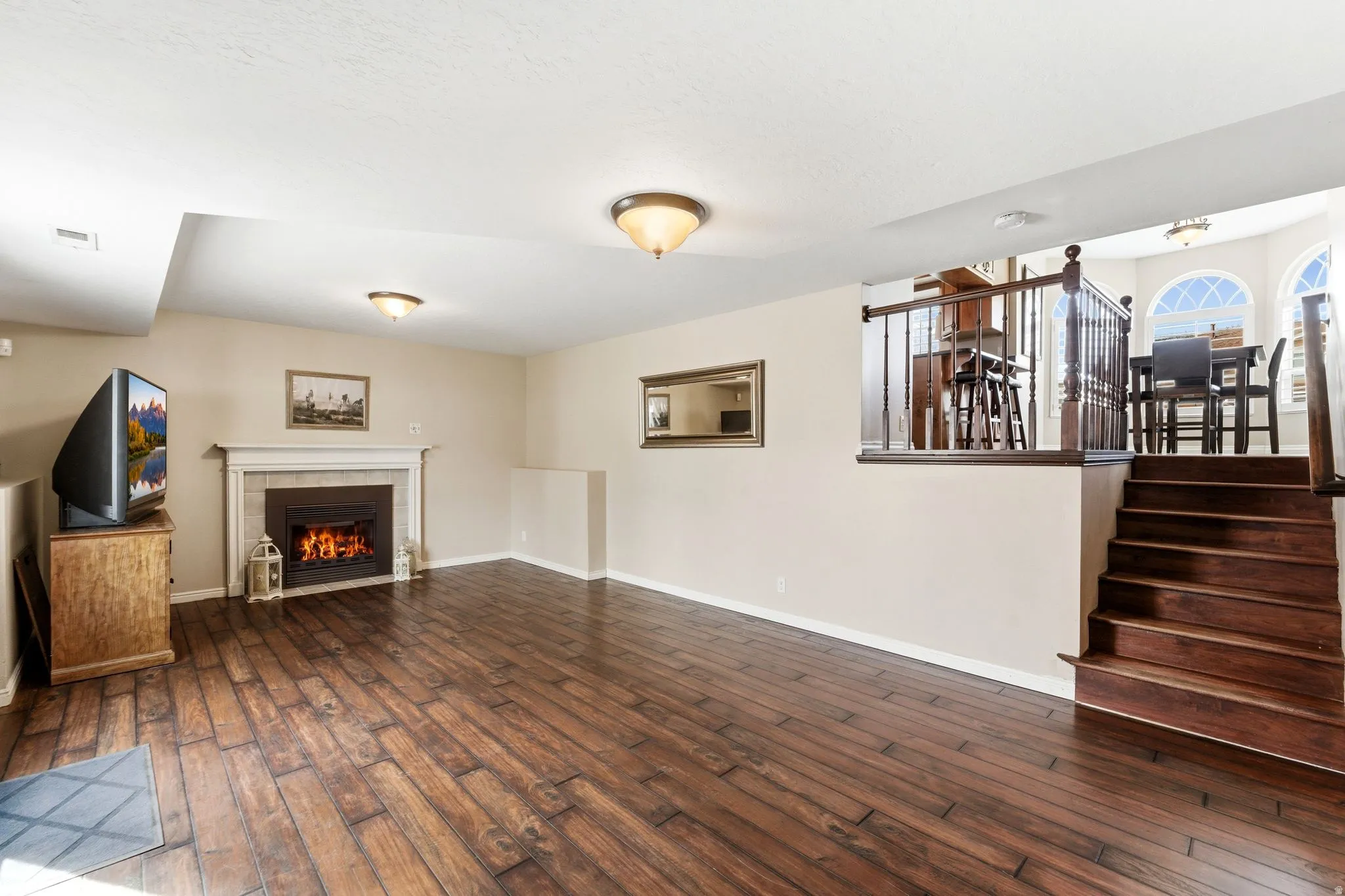 Unfurnished living room with dark wood-style flooring and a tiled fireplace