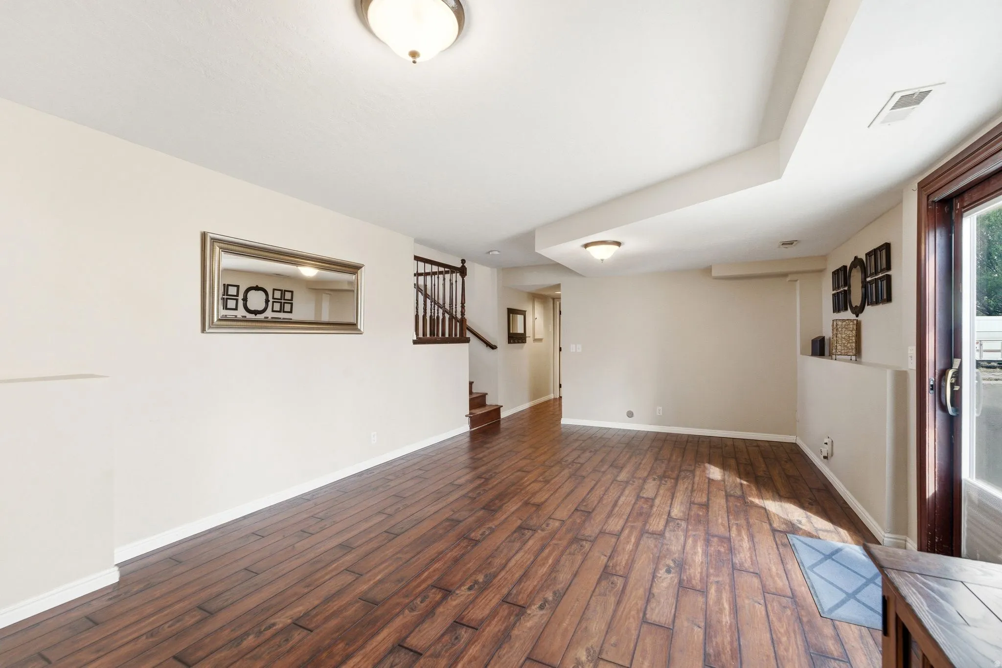 Unfurnished living room featuring stairs and dark wood-style floors