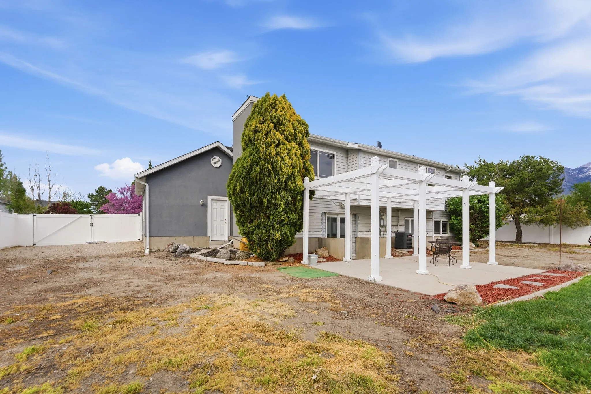 Back of house with a gate, a pergola, a fenced backyard, and a patio
