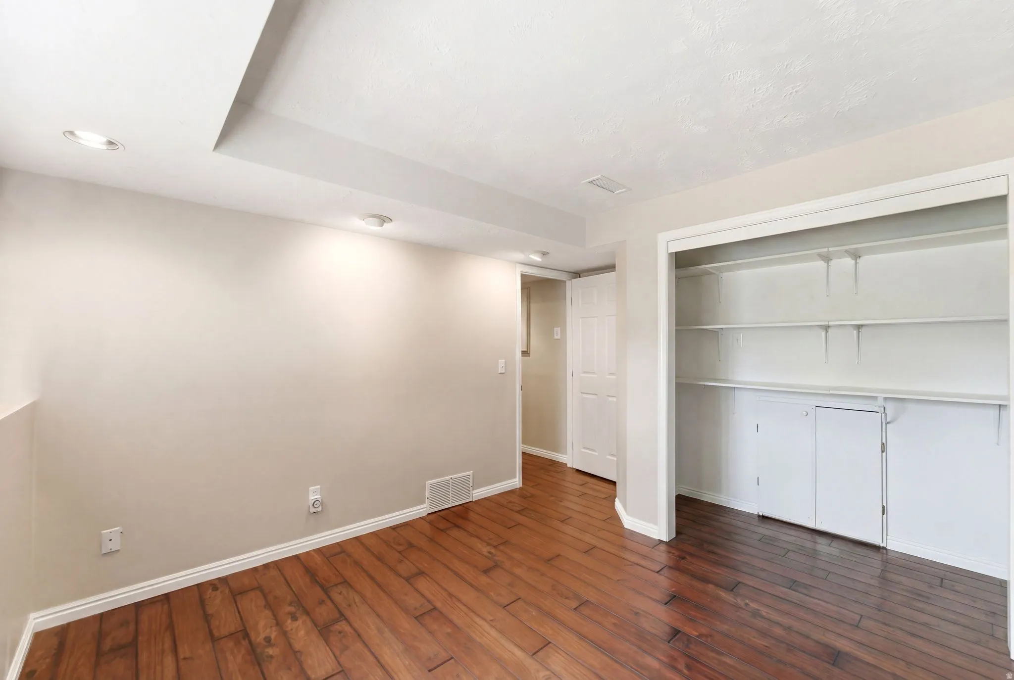 Unfurnished bedroom with dark wood-style flooring, a closet, and recessed lighting