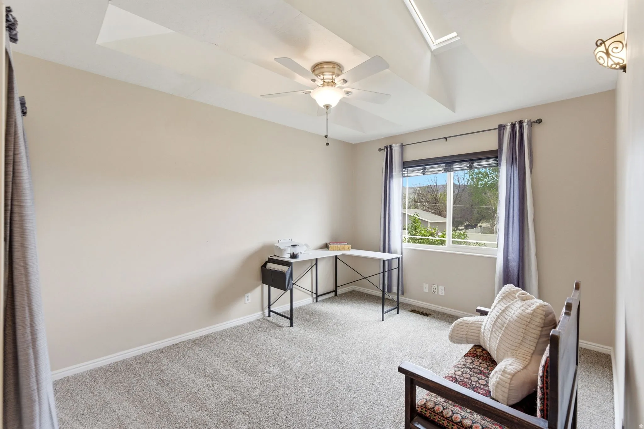 Office with a skylight, light carpet, and ceiling fan