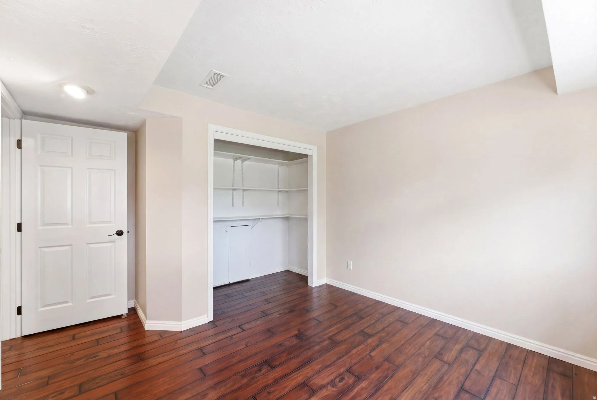 Unfurnished bedroom featuring dark wood finished floors and a closet