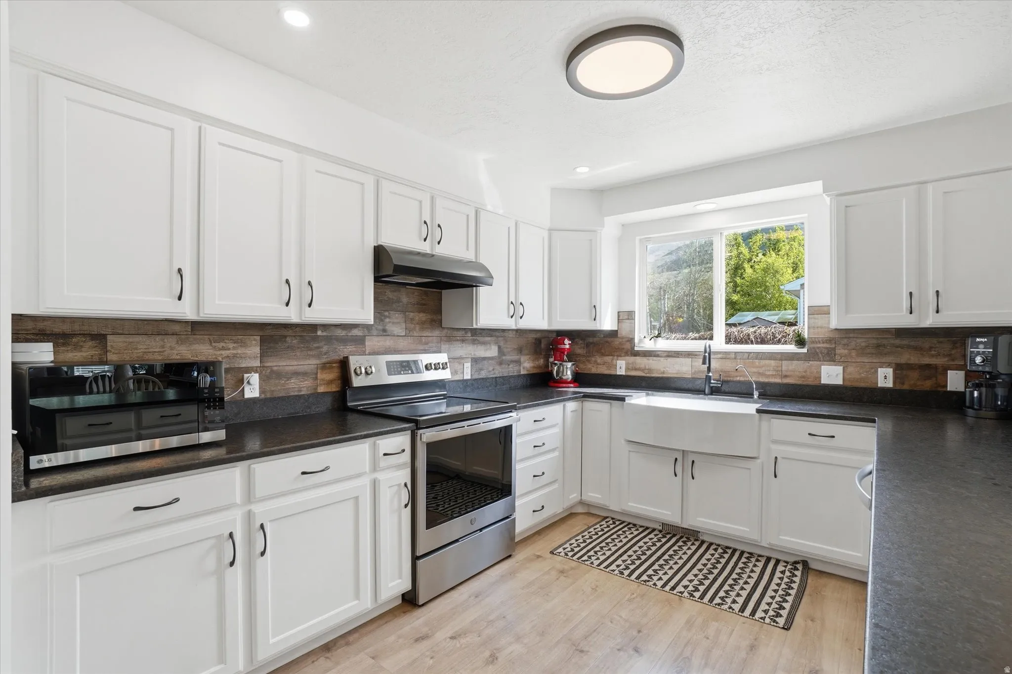 Kitchen with stainless steel appliances, white cabinets, LVP floors, recessed lighting, and leather granite countertops