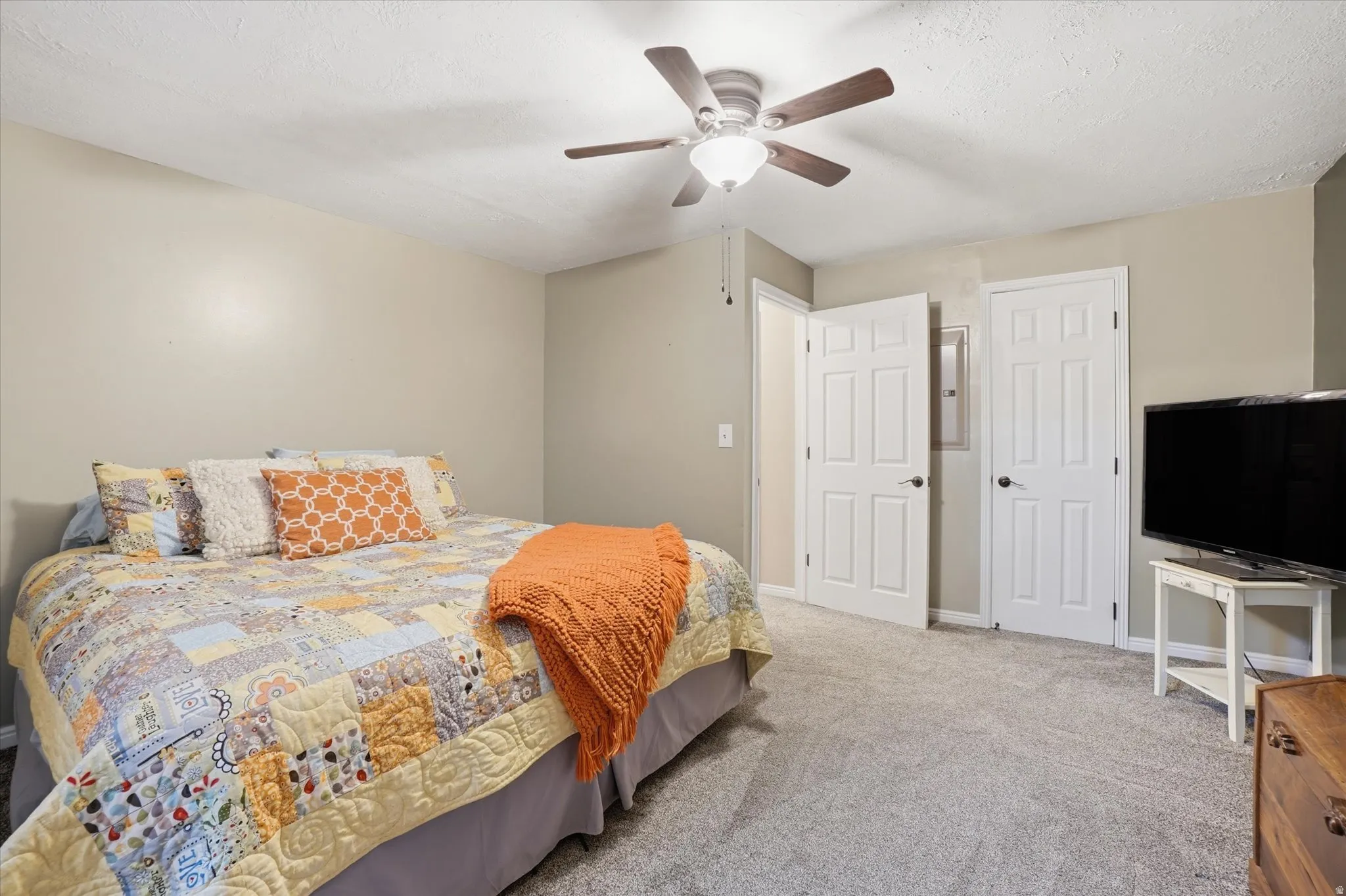 Bedroom with carpet flooring, ceiling fan, and a textured ceiling