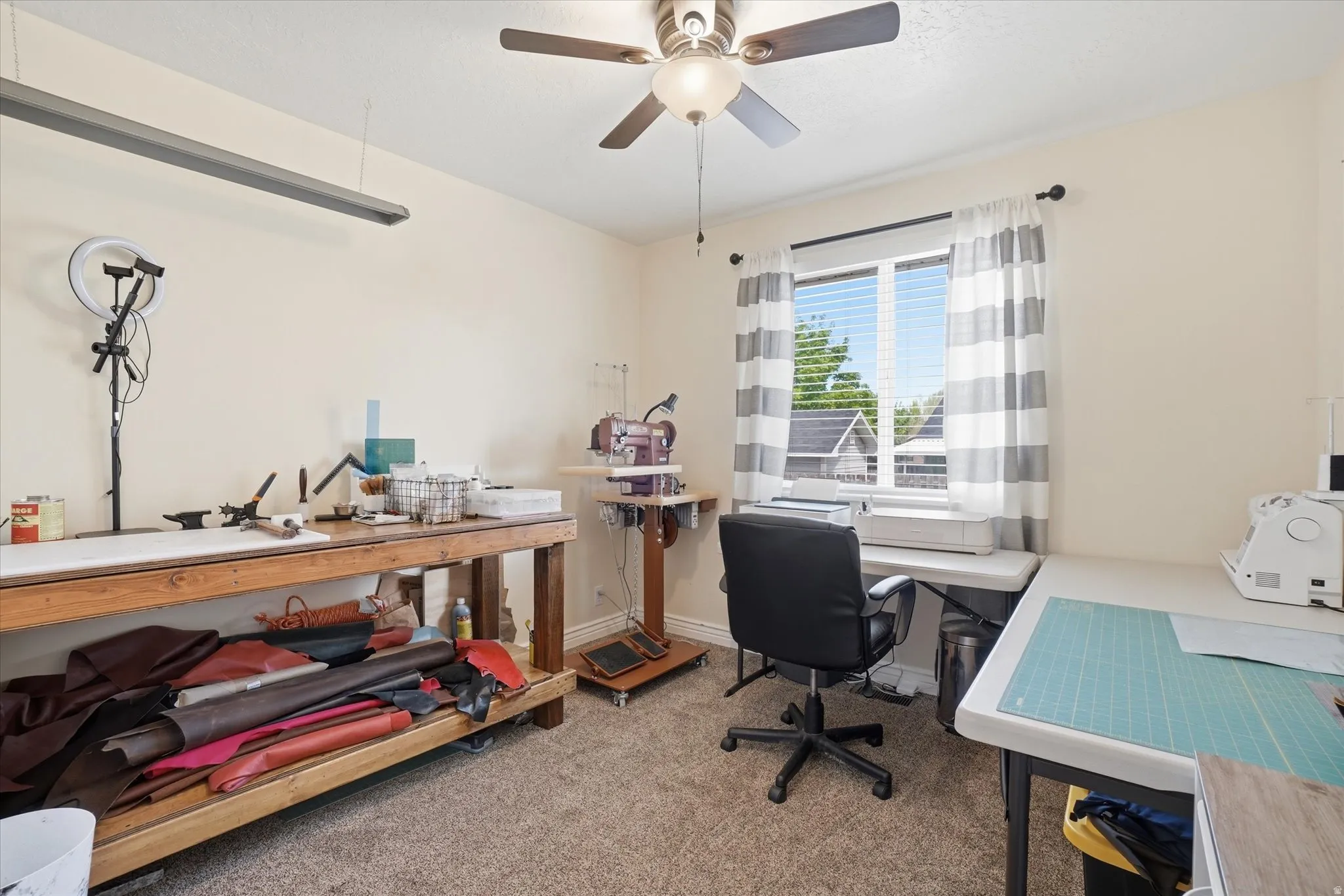 Office area with a ceiling fan and light carpet