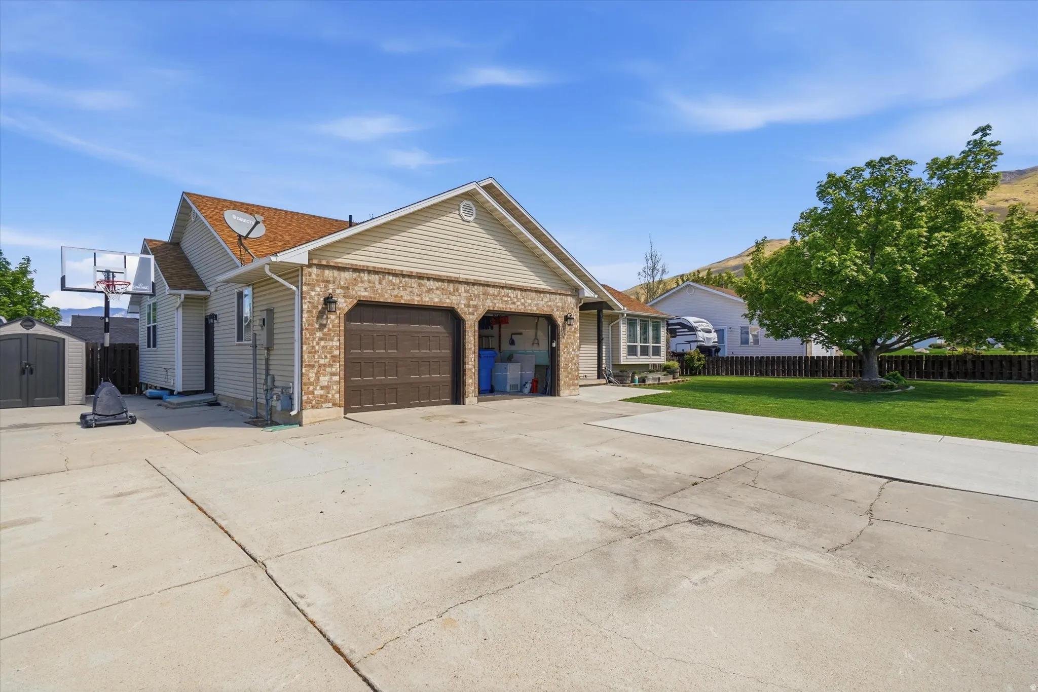 View of front of property featuring concrete driveway, a garage, a storage unit, and brick siding