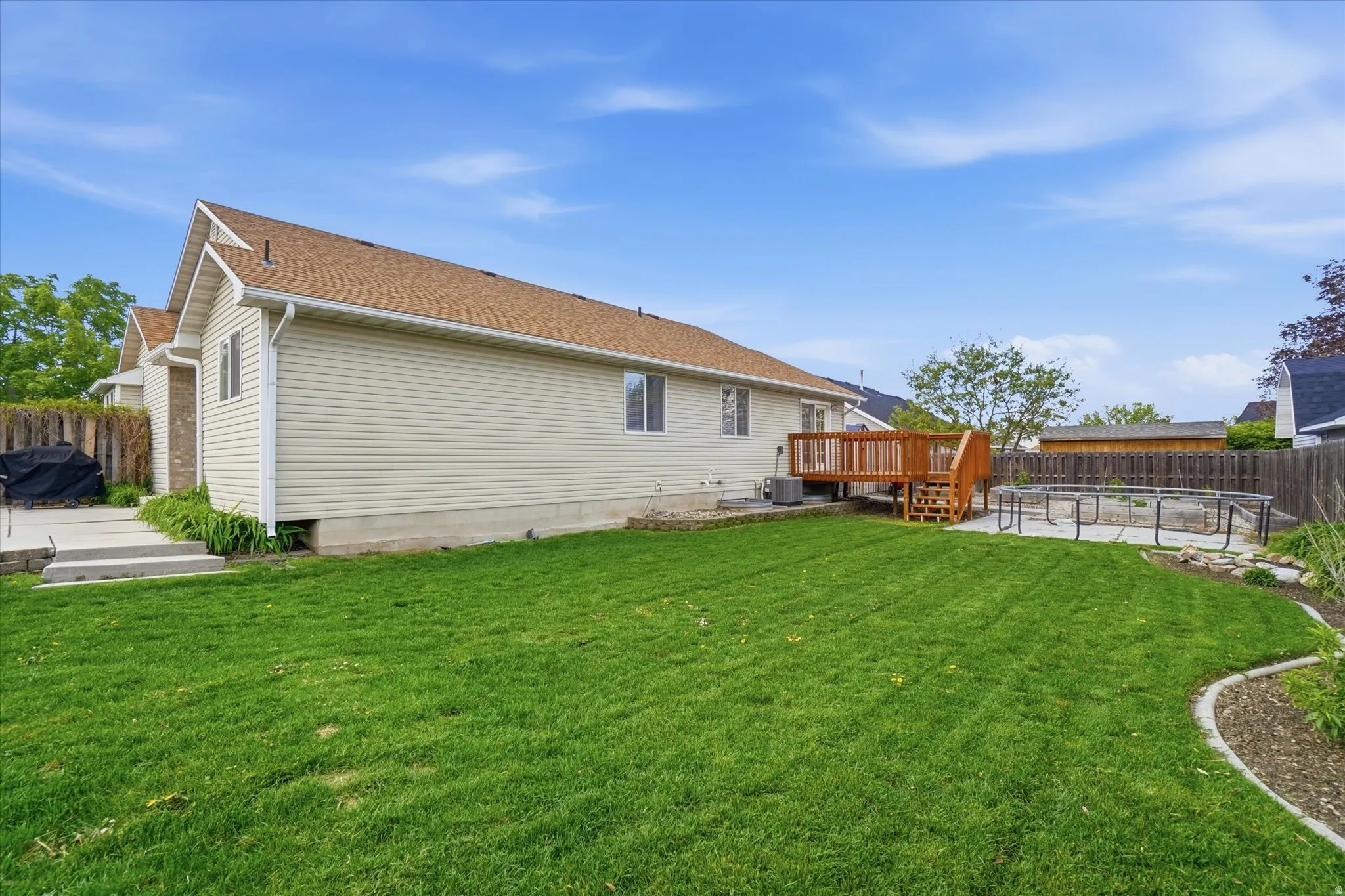 Back of property featuring a wooden deck, a fenced backyard, a patio, and a shingled roof