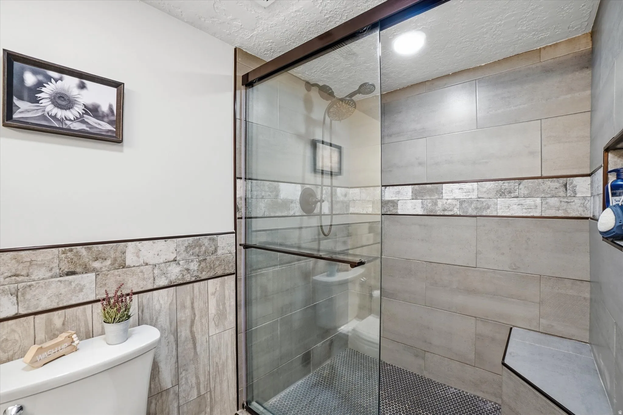 Full bath featuring a stall shower, a textured ceiling, recessed lighting, and tile walls